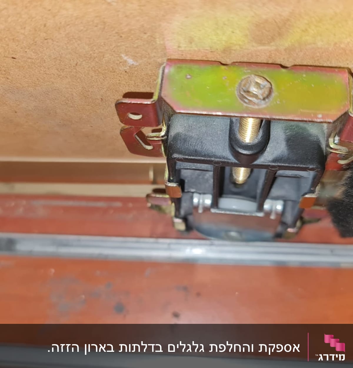 גלגל מתכת מחובר לדלת עץ עם מסילה